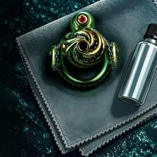 Load image into Gallery viewer, Abyssal Eye Alloy Chastity Cage displayed on a black travel pouch beside a silver bottle